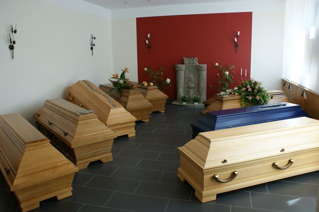 Sargausstellung vor einer roten Wand